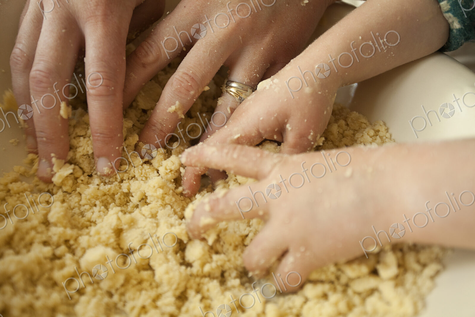 Two pairs of hands mixing ingredients in a bowl, an adult and a child cooking together.