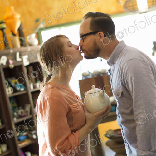 Two people, a couple running an antique store. Small business. Kissing each other.