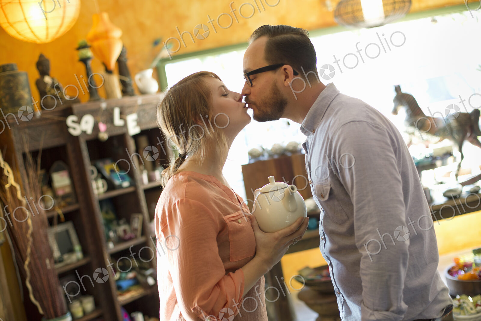 Two people, a couple running an antique store. Small business. Kissing each other.
