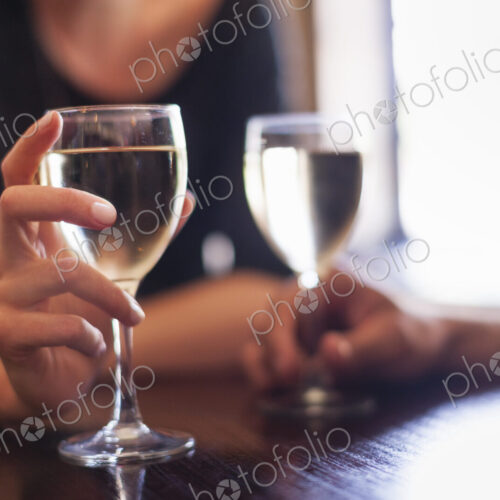 Two people, a couple sitting in a bar having a glass of chilled white wine.