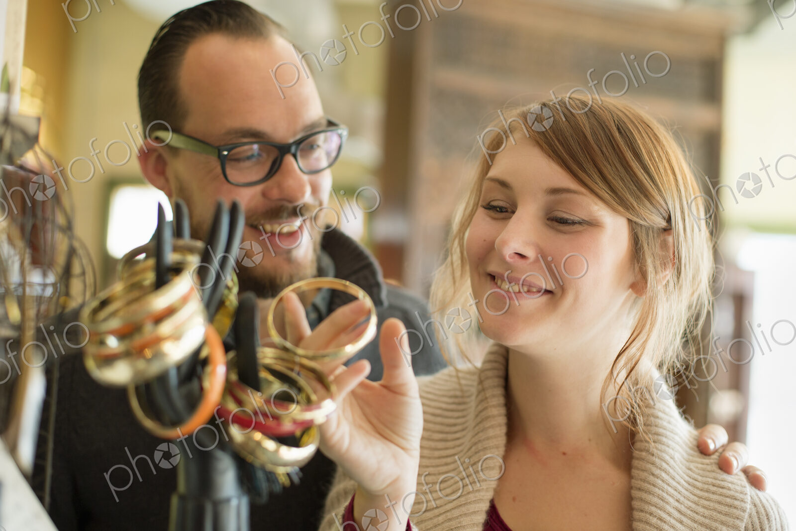 Two people, a man and woman looking at the objects displayed on a mannequin hand,…
