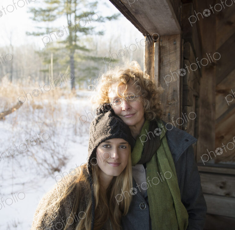 Two people, a mother and daughter, side by side, in the porch of a wooden barn on a…