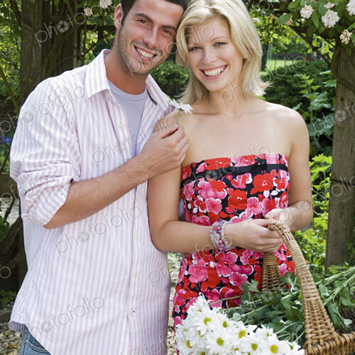 Two people, a smiling couple, in a garden. A young woman carrying a trug of cut flowers. Two people, a smiling couple, in a garden. A young woman carrying a trug of cut flowers.