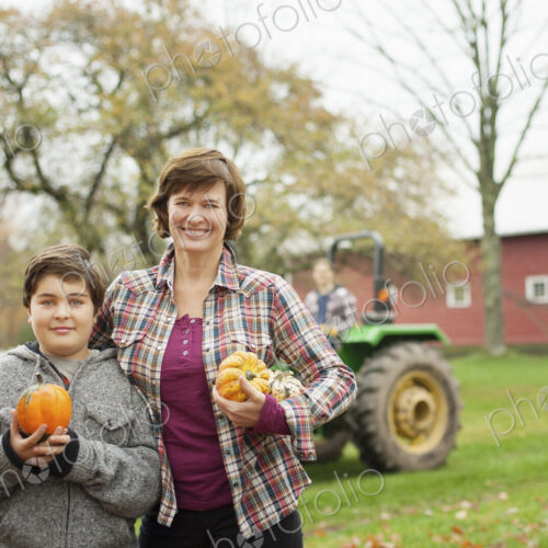 Two people, a woman and a child on an organic farm, carrying harvested vegetables,… Two people, a woman and a child on an organic farm, carrying harvested vegetables,…