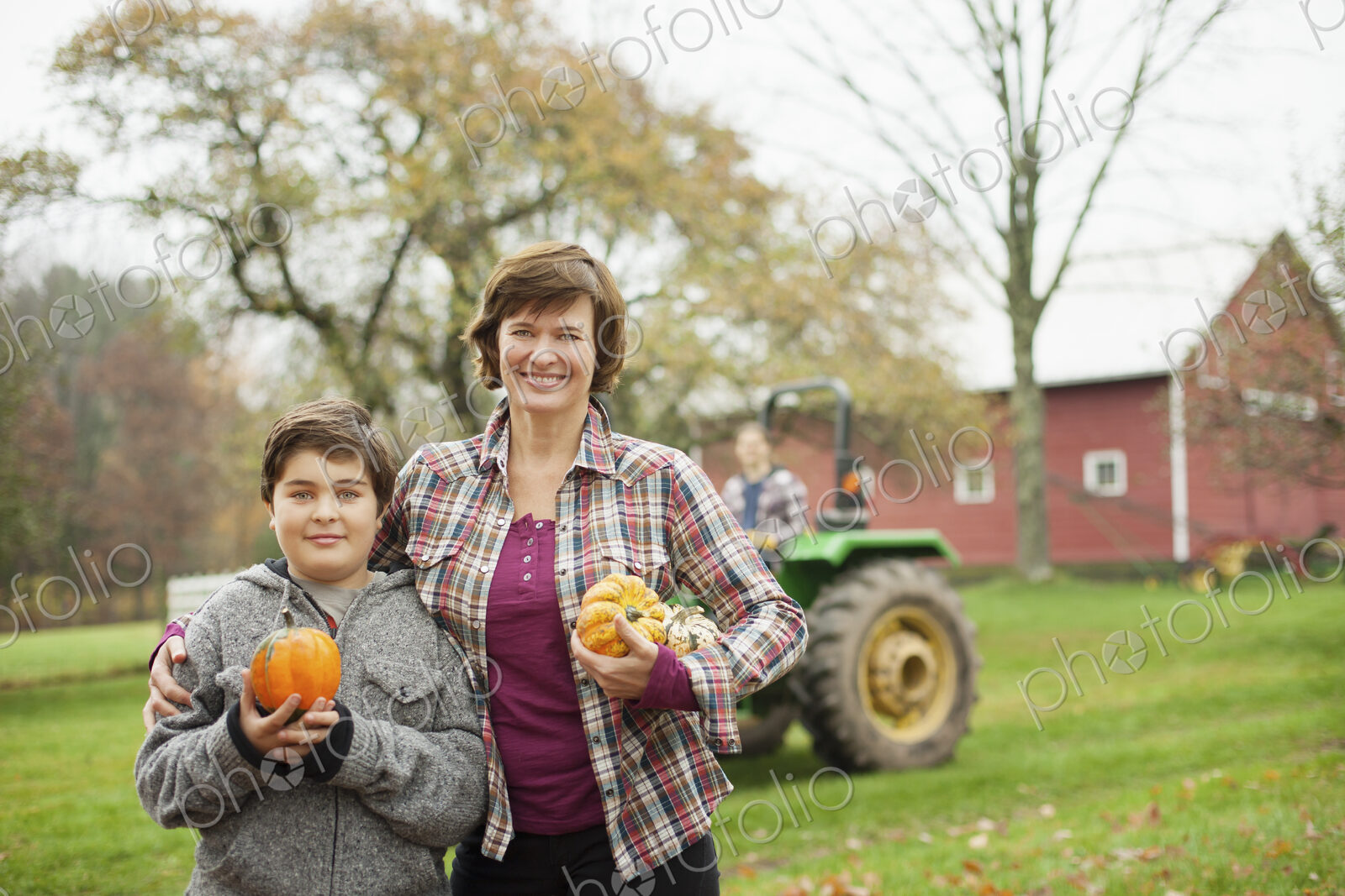 Two people, a woman and a child on an organic farm, carrying harvested vegetables,…