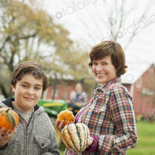Two people, a woman and a child on an organic farm, carrying harvested vegetables,… Two people, a woman and a child on an organic farm, carrying harvested vegetables,…