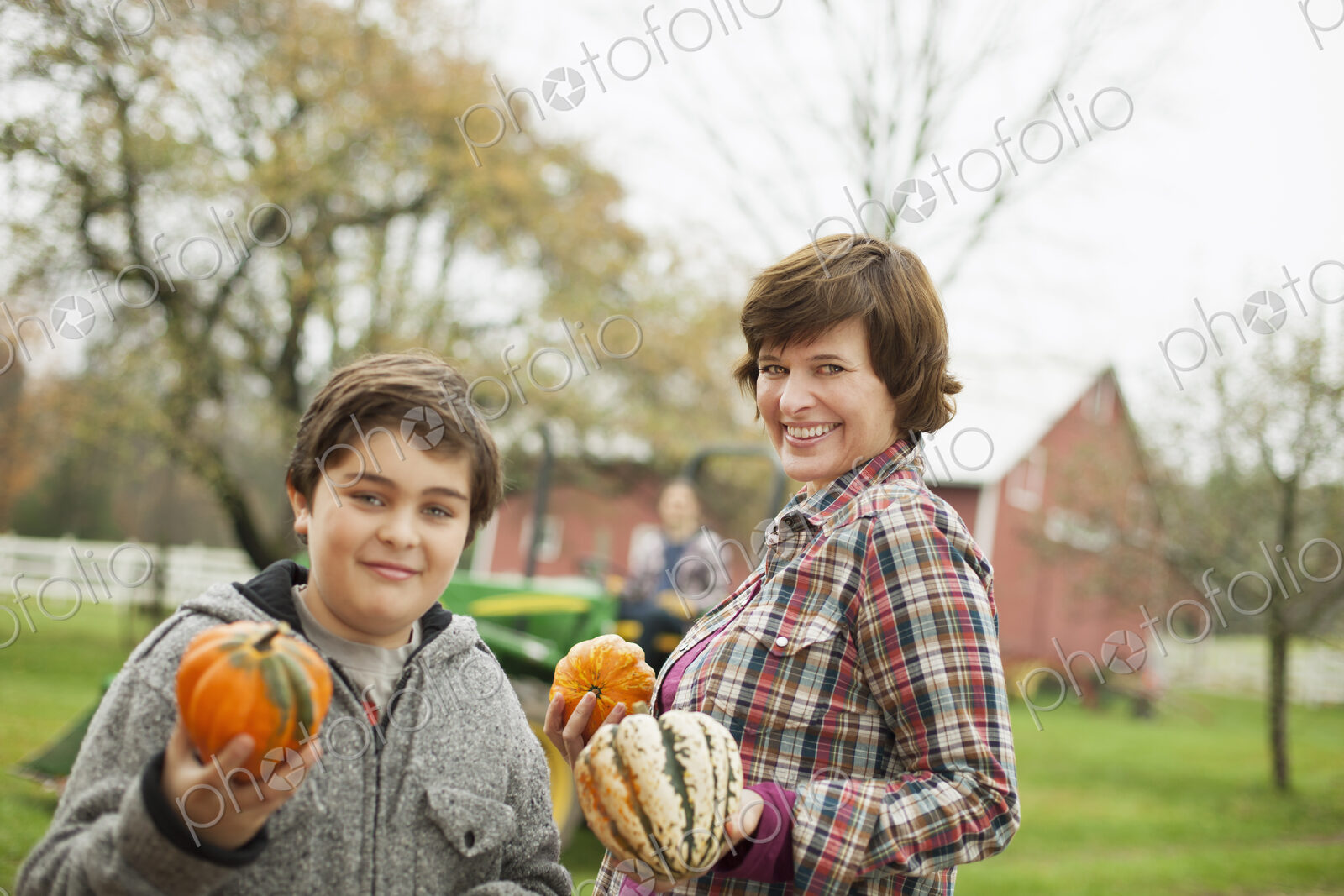 Two people, a woman and a child on an organic farm, carrying harvested vegetables,…