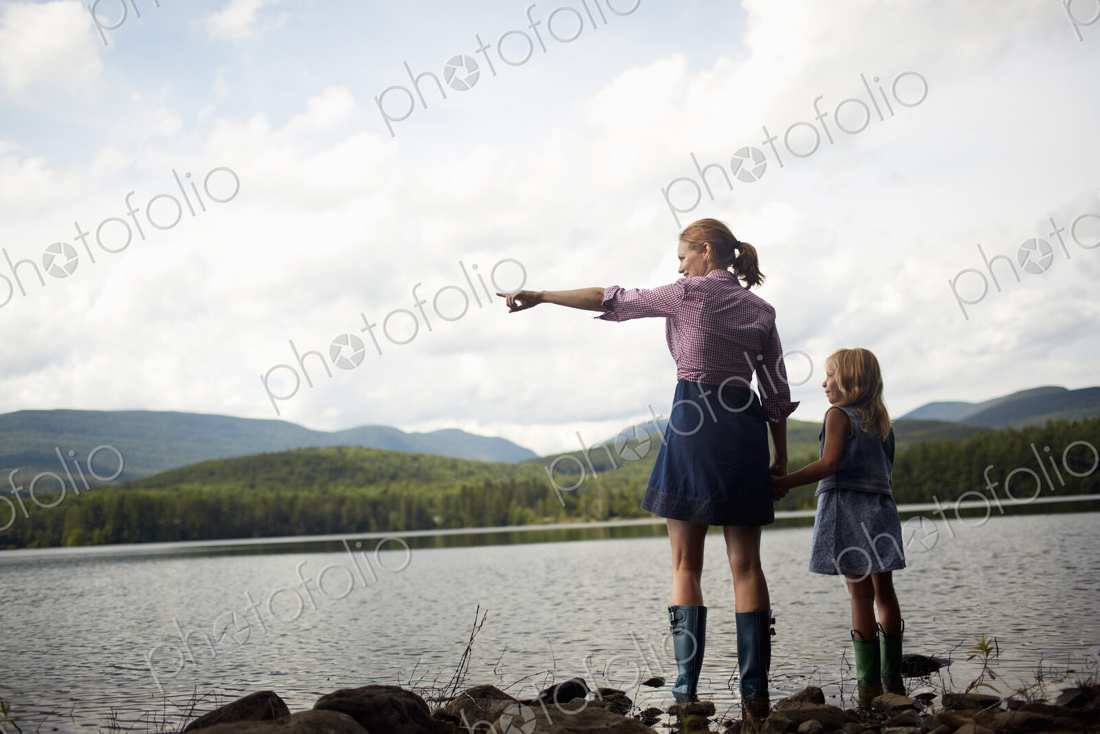 Two people, a woman and a child standing side by side and looking over water.