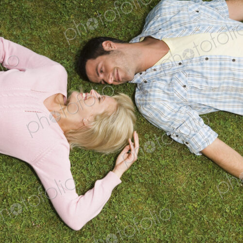 Two people, a young man and woman lying on their backs, heads close together. Two people, a young man and woman lying on their backs, heads close together.