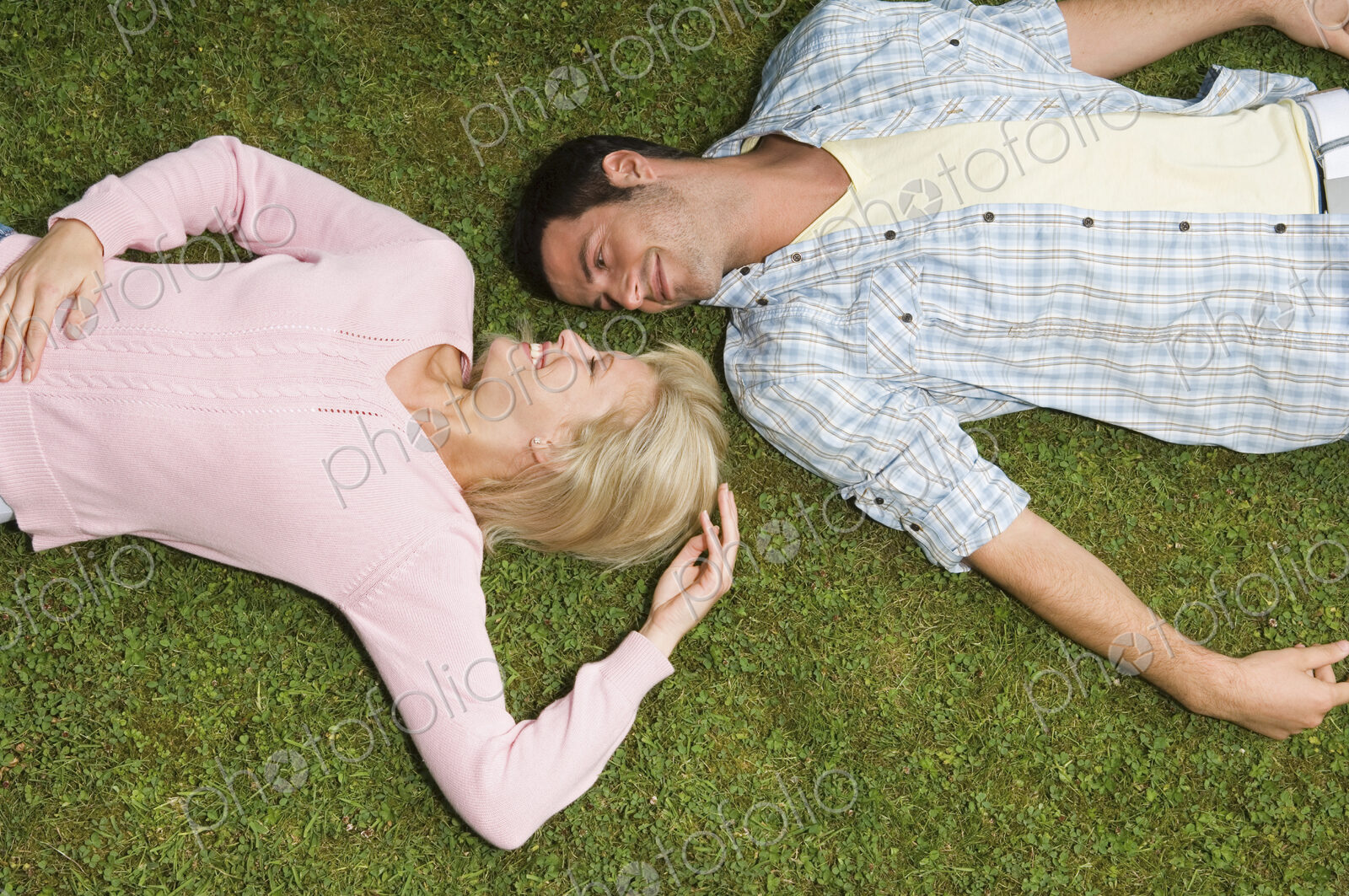 Two people, a young man and woman lying on their backs, heads close together.