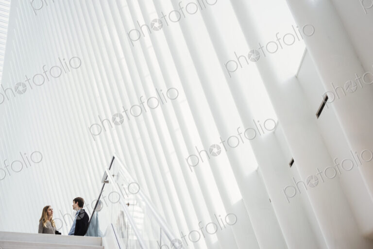 Two people at the top of steps in a tall airy central atrium of a public building.