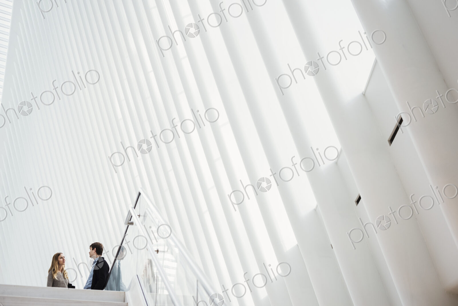 Two people at the top of steps in a tall airy central atrium of a public building.