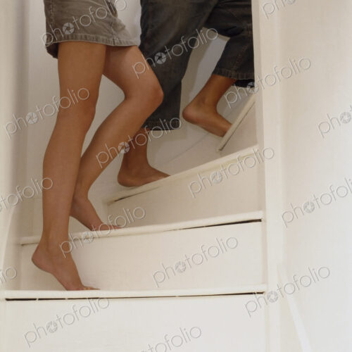 Two people, hand in hand, walking up the stairs. A man and a woman, viewed from the… Two people, hand in hand, walking up the stairs. A man and a woman, viewed from the…