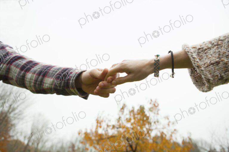 Two people holding hands, a couple outdoors.