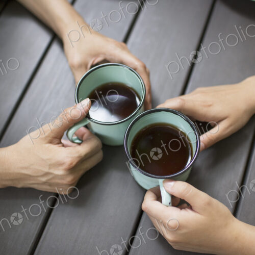 Two people seated at a table, drinking coffee, viewed from above. Two people seated at a table, drinking coffee, viewed from above.