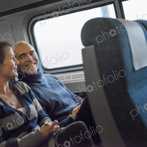 Two people sitting in a railway carriage, smiling. Taking a train journey. Two people sitting in a railway carriage, smiling. Taking a train journey.