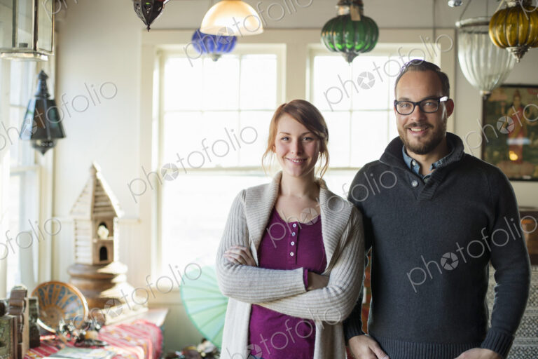 Two people standing in a store full of antique objects, a couple running a business.