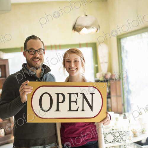 Two people standing in a store full of antique objects, a couple running a business.… Two people standing in a store full of antique objects, a couple running a business.…