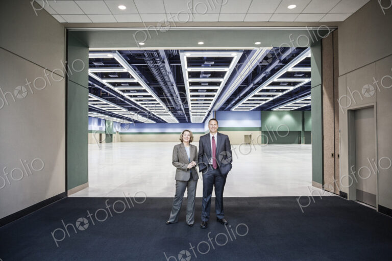 Two people standing in the entrance to a large convention center arena.