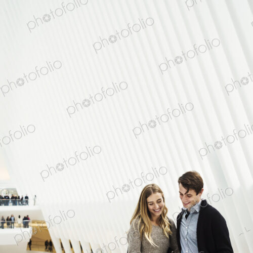 Two people standing on a balcony sharing a phone screen, with an overview of the… Two people standing on a balcony sharing a phone screen, with an overview of the…