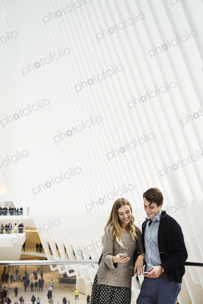 Two people standing on a balcony sharing a phone screen, with an overview of the…