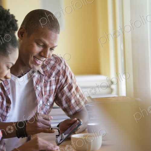 Two people using a digital tablet, seated close together at a cafe. Coffee cups. Two people using a digital tablet, seated close together at a cafe. Coffee cups.