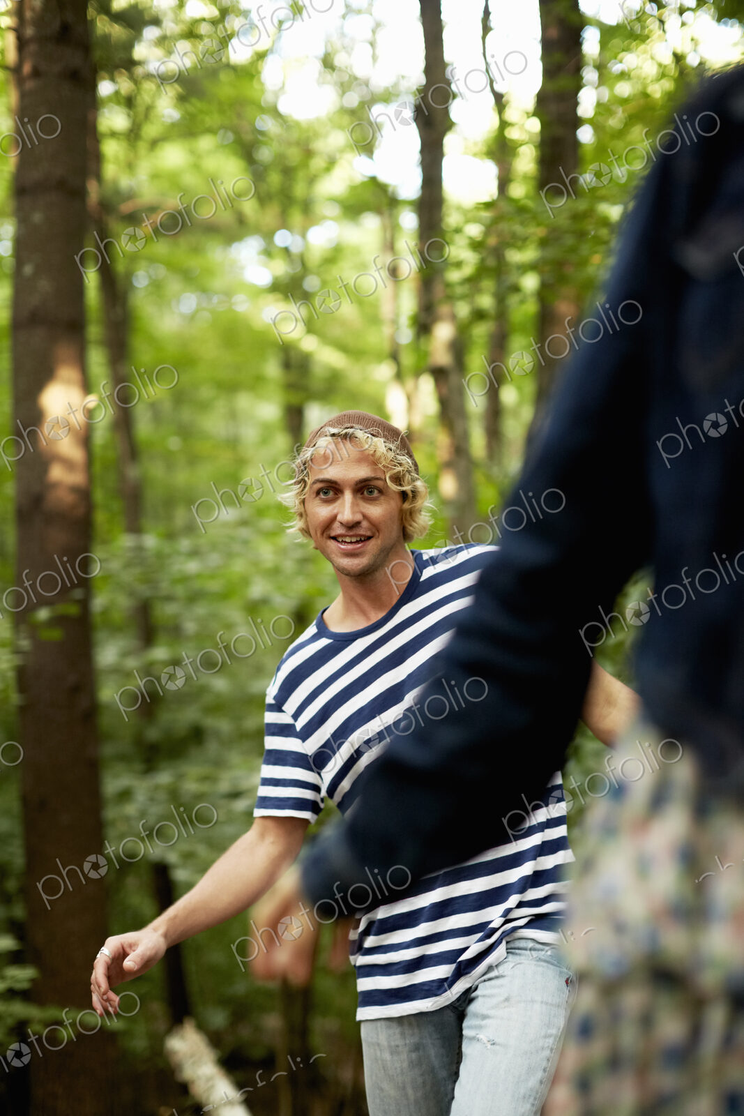 Two people walking along a fallen tree trunk in the woods.