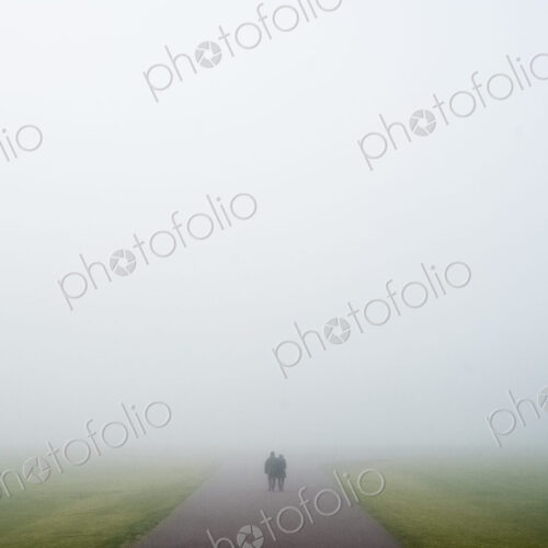 Two people walking along a rural road on a misty day. Two people walking along a rural road on a misty day.