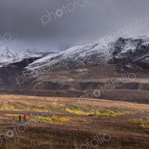 Two people walking towards Denali or Mount McKinley under overcast grey skies. Two people walking towards Denali or Mount McKinley under overcast grey skies.