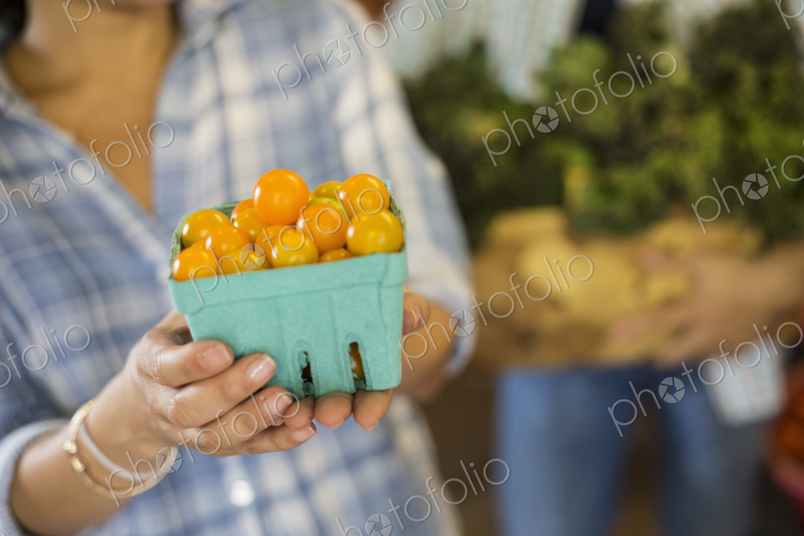 Two people with baskets of tomatoes and curly green leafy vegetables. Working on an…