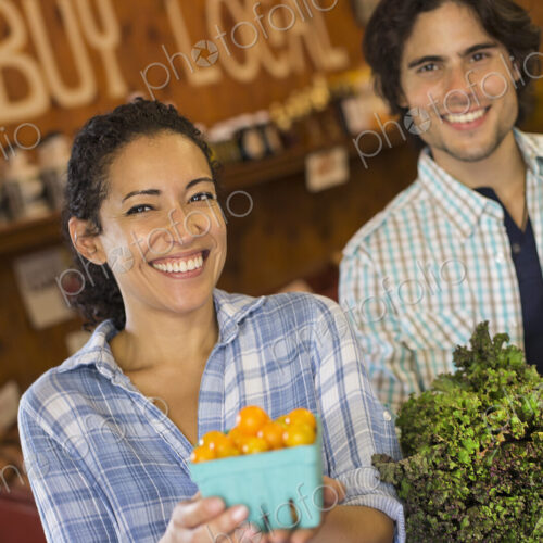 Two people with baskets of tomatoes and curly green leafy vegetables. Working on an… Two people with baskets of tomatoes and curly green leafy vegetables. Working on an…