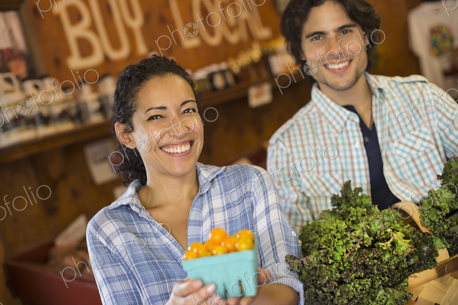 Two people with baskets of tomatoes and curly green leafy vegetables. Working on an…