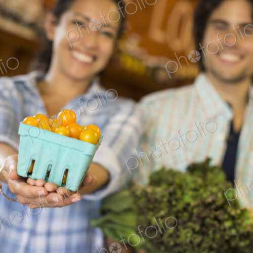 Two people with baskets of tomatoes and curly green leafy vegetables. Working on an… Two people with baskets of tomatoes and curly green leafy vegetables. Working on an…