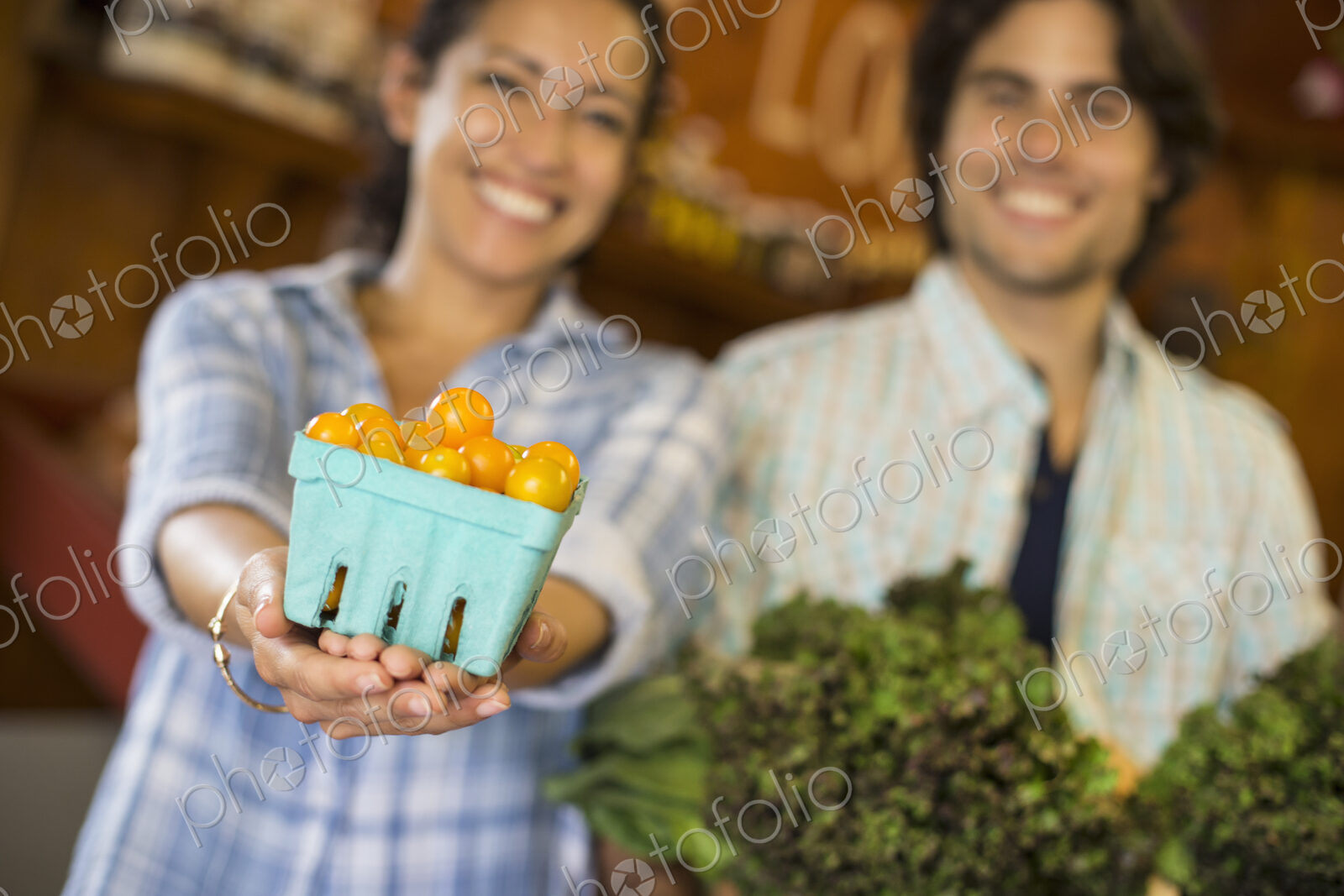 Two people with baskets of tomatoes and curly green leafy vegetables. Working on an…