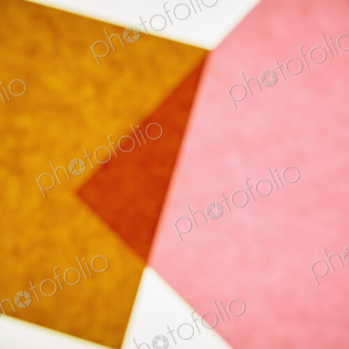 Two pieces of recycled construction paper, brown and pink with a small overlapping…