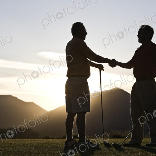 Two senior friends approach the first tee of a golf course at sunrise. Two senior friends approach the first tee of a golf course at sunrise.