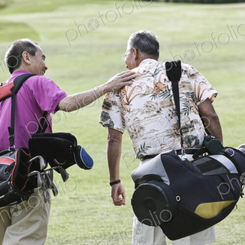 Two senior friends golfing and walking on a fairway toward their next shots. Two senior friends golfing and walking on a fairway toward their next shots.