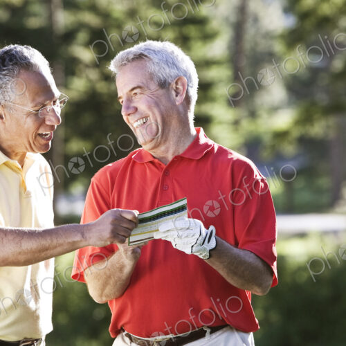 Two senior friends laughing about a golf score on a local golf course. Two senior friends laughing about a golf score on a local golf course.