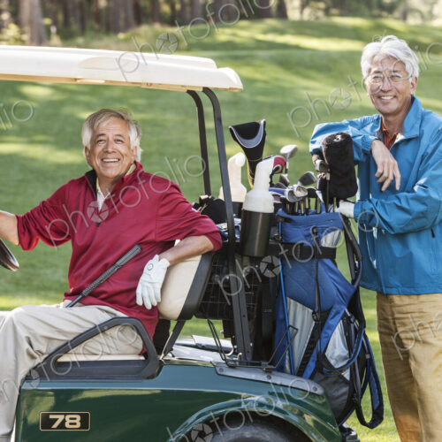 Two senior male golfing buddies and their golf cart and clubs.