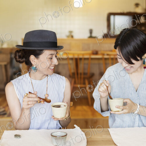 Two smiling Japanese women eating in a vegetarian cafe. Two smiling Japanese women eating in a vegetarian cafe.