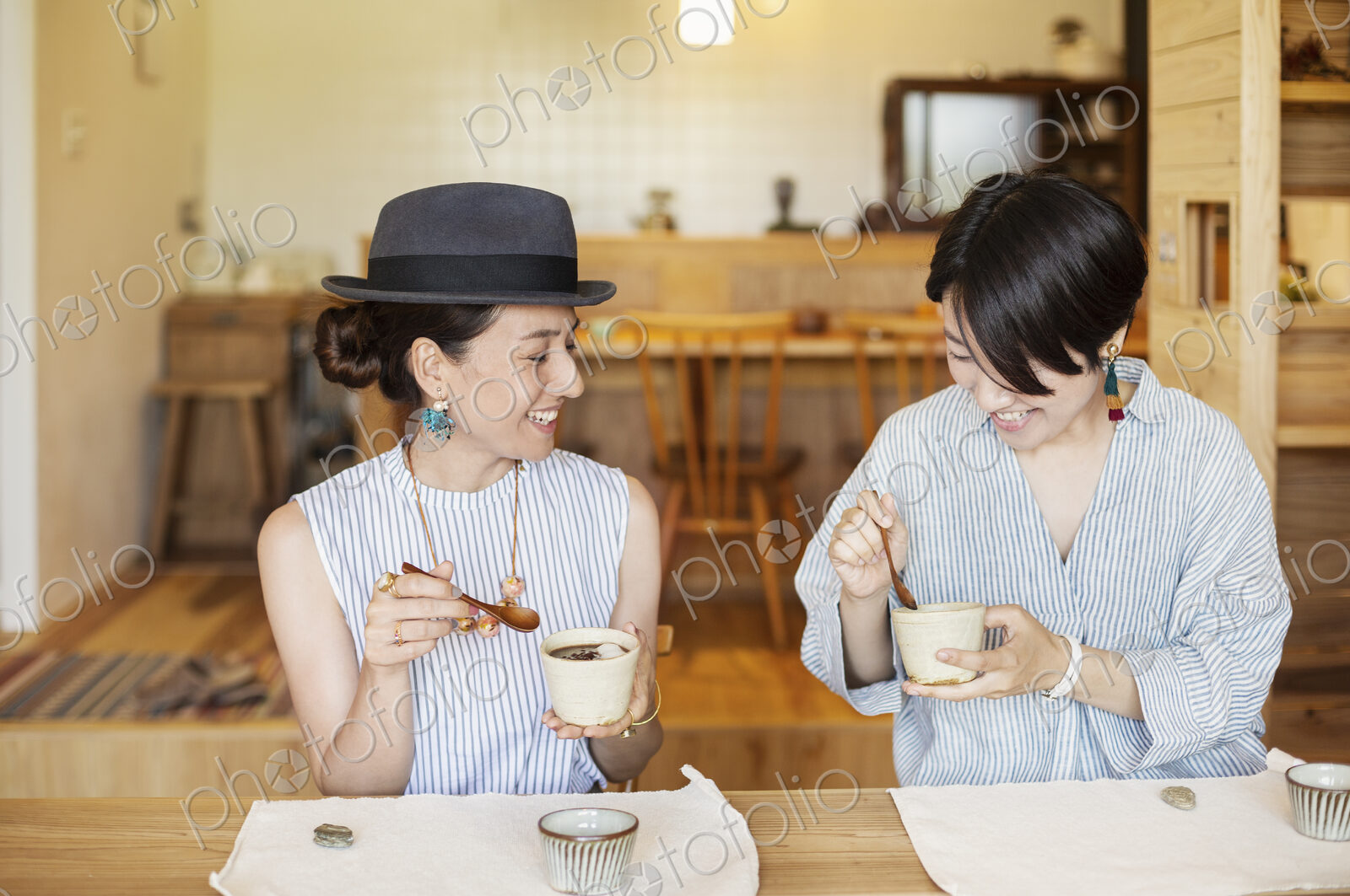 Two smiling Japanese women eating in a vegetarian cafe.