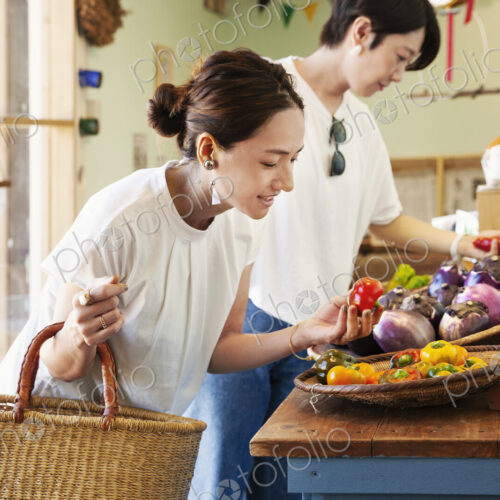 Two smiling Japanese women looking at fresh vegetables in a farm shop. Two smiling Japanese women looking at fresh vegetables in a farm shop.