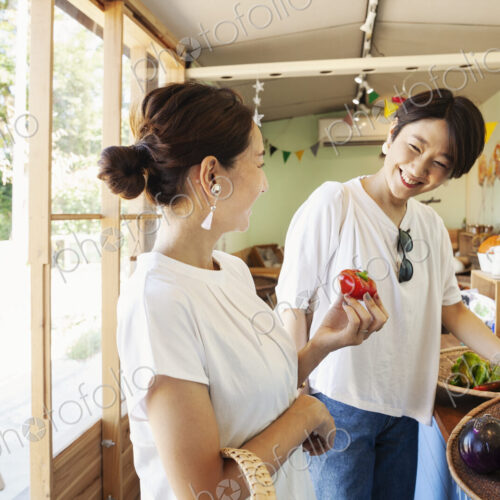 Two smiling Japanese women looking at fresh vegetables in a farm shop. Two smiling Japanese women looking at fresh vegetables in a farm shop.