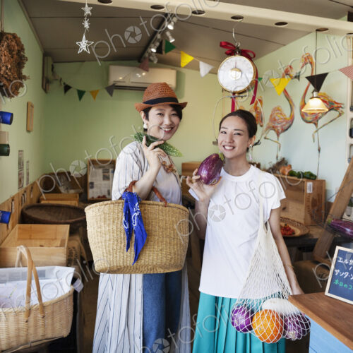 Two smiling Japanese women standing in a farm shop, looking at camera. Two smiling Japanese women standing in a farm shop, looking at camera.