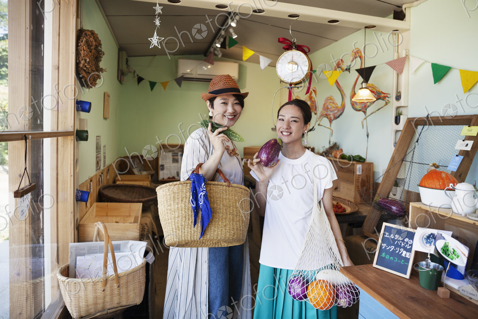 Two smiling Japanese women standing in a farm shop, looking at camera.