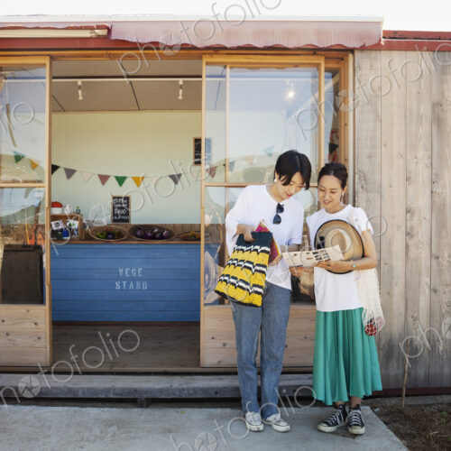 Two smiling Japanese women standing outside a farm shop. Two smiling Japanese women standing outside a farm shop.