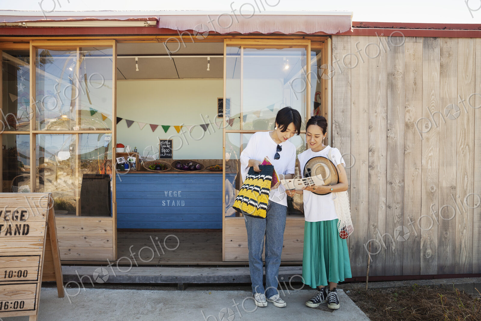 Two smiling Japanese women standing outside a farm shop.