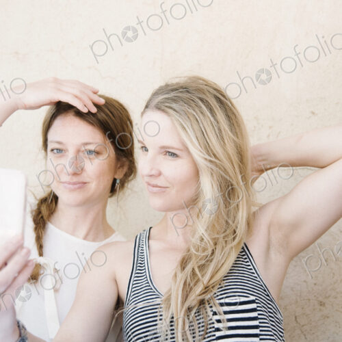 Two smiling women taking a selfie with a cell phone. Two smiling women taking a selfie with a cell phone.