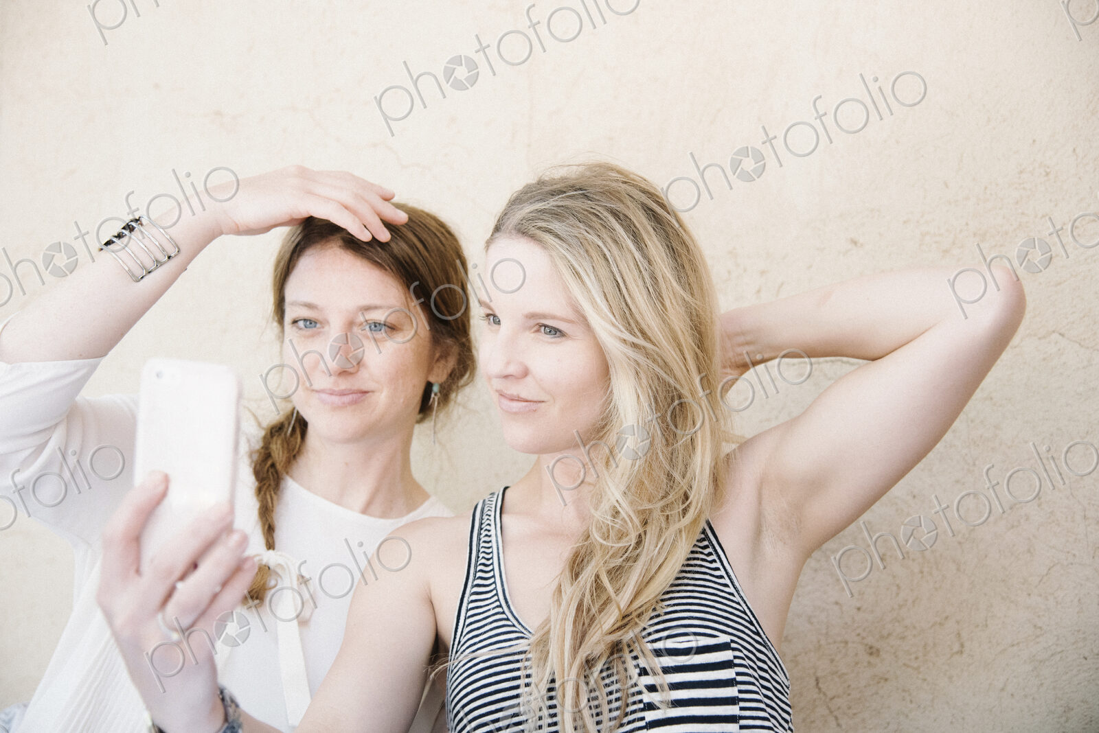 Two smiling women taking a selfie with a cell phone.