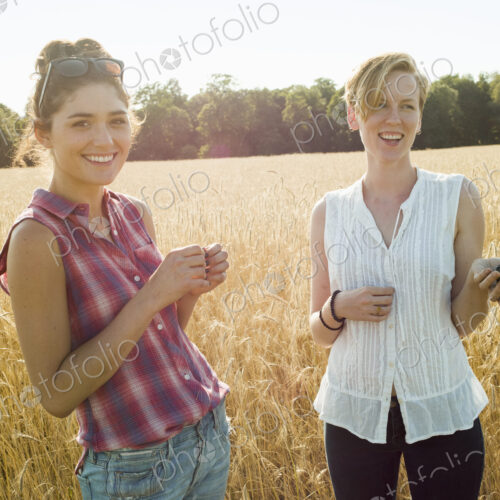 Two smiling young women in a cornfield, one with smart phone. Two smiling young women in a cornfield, one with smart phone.